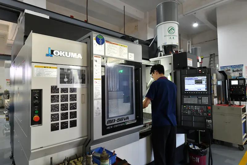 A professional technician operating a specialized 2-shot injection molding machine at GBM manufacturing facility.